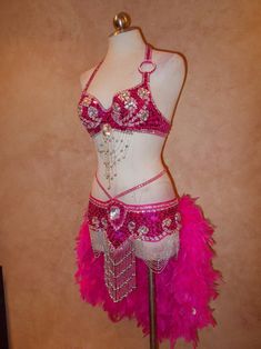 a woman's belly dance costume on display in a store window, with pink feathers and beads