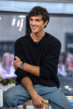 a smiling man sitting on top of a wooden chair