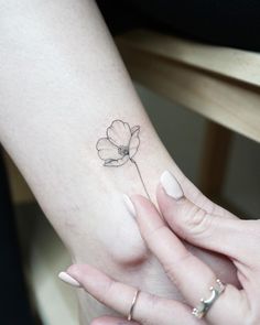 a woman's arm with a small flower tattoo on the left side of her wrist