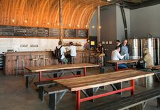 people sitting at tables in a restaurant with wooden walls and beams on the ceiling above them