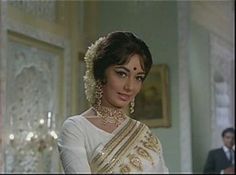 a woman in a white sari and gold jewelry