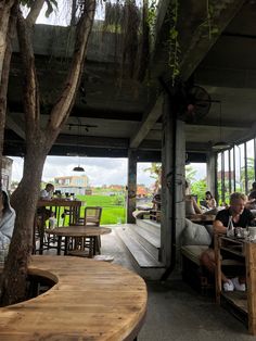 people are sitting at tables in a restaurant with wooden benches and chairs around the table