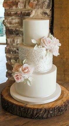 a three tiered white wedding cake with pink flowers