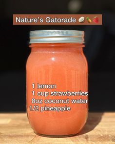 a jar filled with orange liquid sitting on top of a wooden table