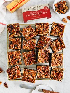 pecan bars on a cooling rack next to a box of butter and spoons