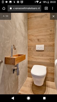 a white toilet sitting inside of a bathroom next to a wooden counter top under a faucet