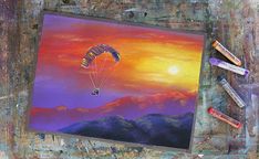 an acrylic painting of a paraglider in the sky at sunset with crayons and markers