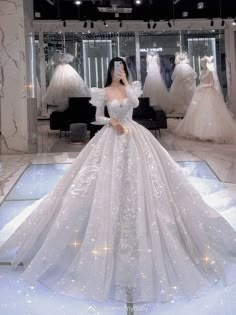 a woman standing in front of a dress on display at a bridal shop wearing a white gown with sequins