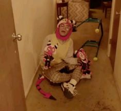 a person sitting on the floor in a room with some balls and tennis rackets