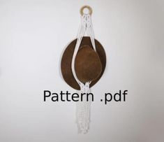 a brown hat hanging from the side of a white wall with a chain attached to it