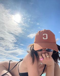 a woman laying on the beach wearing a hat and sunglasses