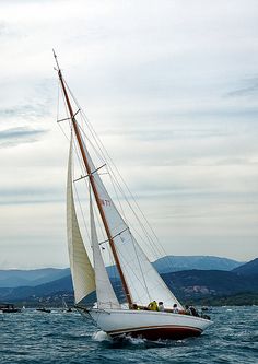 a sailboat sailing on the water with mountains in the background