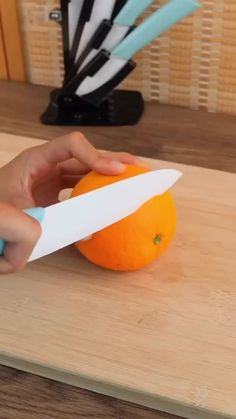 a person cutting an orange with a knife