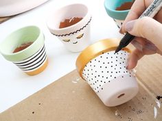 someone is painting their coffee cups with brown and white dots on the cup liners