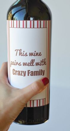 a woman holding up a bottle of wine that says, this nine pairs well with crazy family