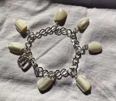 a bracelet with several charms on it sitting on top of a white cloth covered bed