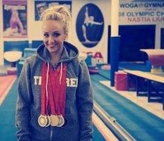 a woman standing in a gym with medals around her neck and wearing a red scarf