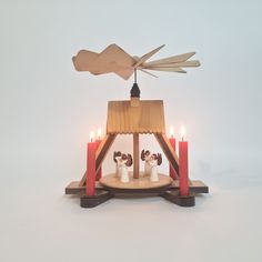 a small wooden structure with candles in front of it and a bird flying over the top