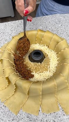 a person cutting noodles with a knife and fork in a bowl on a counter top