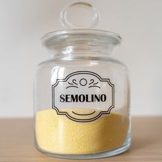 a glass jar filled with yellow sand sitting on top of a wooden table