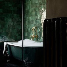 a bath tub sitting next to a green tiled wall