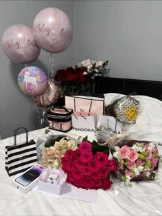 flowers and balloons on a bed in a room with a bag, purse, card holder, phone and other items