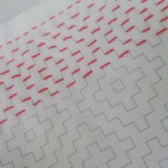 a close up view of some red and white lines on a piece of paper that has been stitched together