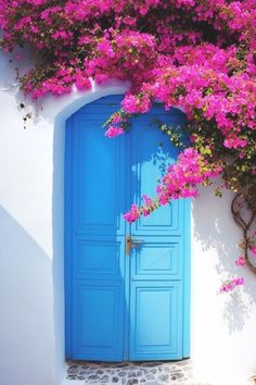 an open blue door with pink flowers growing over it