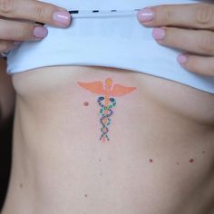 a woman's stomach with a medical symbol tattoo on the side of her belly