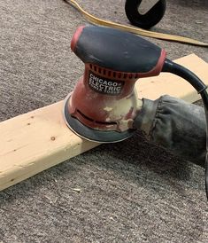 a person using a sander on a piece of wood that is laying on the ground