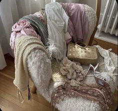 a pile of clothes sitting on top of a wooden floor next to a chair and window