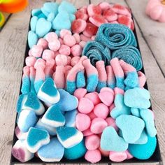 a tray filled with marshmallows and candy hearts on top of a wooden table