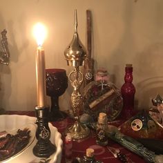 a table topped with lots of different types of items next to a lit candlestick