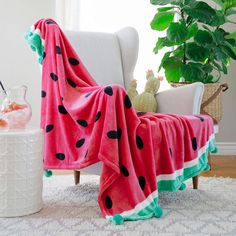 a watermelon blanket sitting on top of a chair next to a potted plant