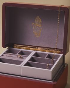 an open jewelry box with two pairs of rings in it and a chain hanging from the lid