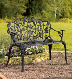 a metal bench sitting in the middle of a field with purple flowers on top of it