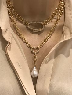 a close up of a person wearing a gold necklace with pearls on it and a chain around the neck