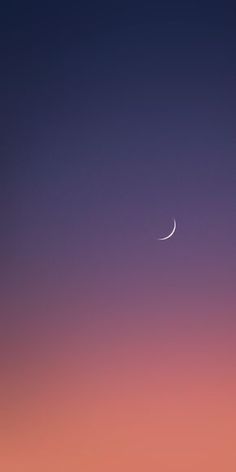 the moon is seen in the sky at dusk with pink and purple hues behind it