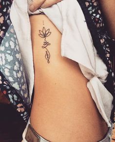 a woman's lower back tattoo with a small flower on the left side of her stomach