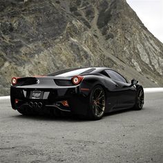 a black sports car parked in front of a mountain