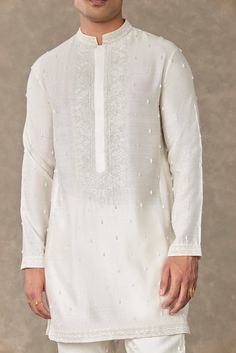 Achieve a sophisticated look with this short kurta featuring exquisite pearl drop detailing and tone-on-tone embroidery in resham, cutdana, and silver badla work. The full sleeves, mandarin collar, concealed placket, and practical pocket detail enhance its charm. Pair it with the comfortable plain straight pants that feature pocket detailing, an elasticated waist, and a front closure for a stylish and convenient outfit. Short Kurta For Men, Kurta And Pants, Caribbean Fashion, Kurta Men, Short Kurta, Embellished Shorts, Lakme Fashion Week, Couples Poses, Tone On Tone