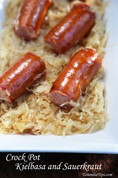 four hotdogs sitting on top of sauerkraut in a white dish