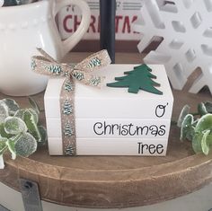 a small christmas tree sitting on top of a white box next to a cup and snowflakes