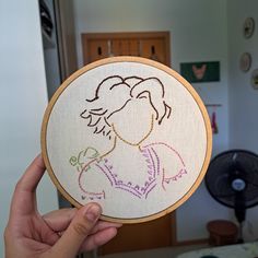 a person holding up a cross - stitch hoop with an image of a woman's face on it