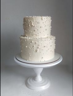 a three tiered white cake with pearls on it