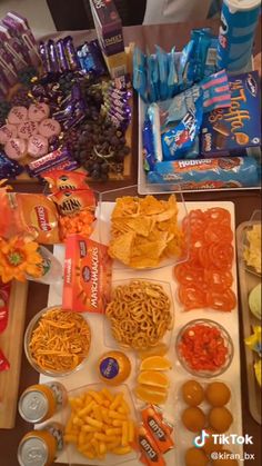 the table is full of snacks and candys, including oranges, cheetos, chips