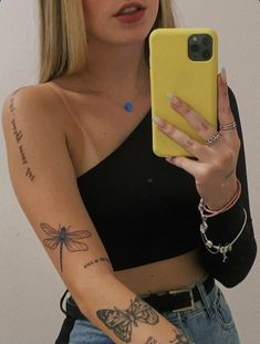 a woman is holding up her phone in front of her face and showing off her tattoos