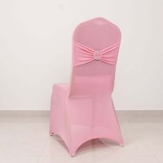 a pink chair with a bow on it's back sitting in front of a white wall