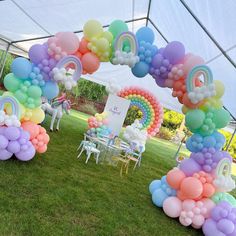 an arch made out of balloons in the shape of rainbows and unicorns on grass