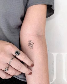 a woman's arm with a small heart tattoo on the left side of her arm